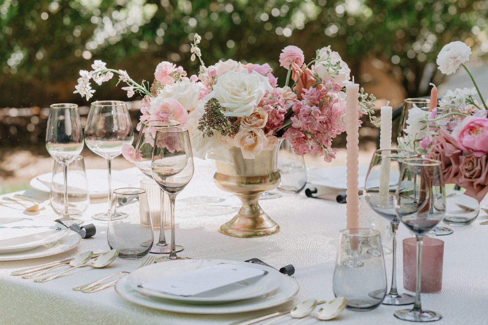 Luxurious table setting with pink and white floral centerpiece and crystal wine glasses.