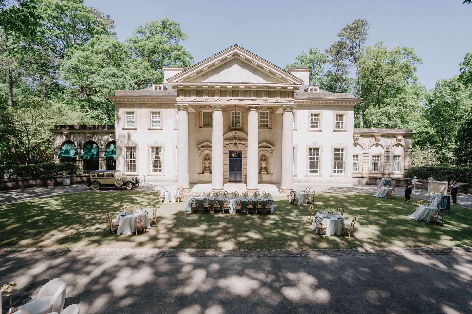 Grand neoclassical mansion with white columns and symmetrical facade in a lush garden setting.
