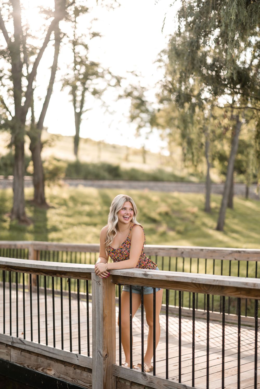 A portrait session on a wooden bridge in a park during golden hour with soft natural lighting.