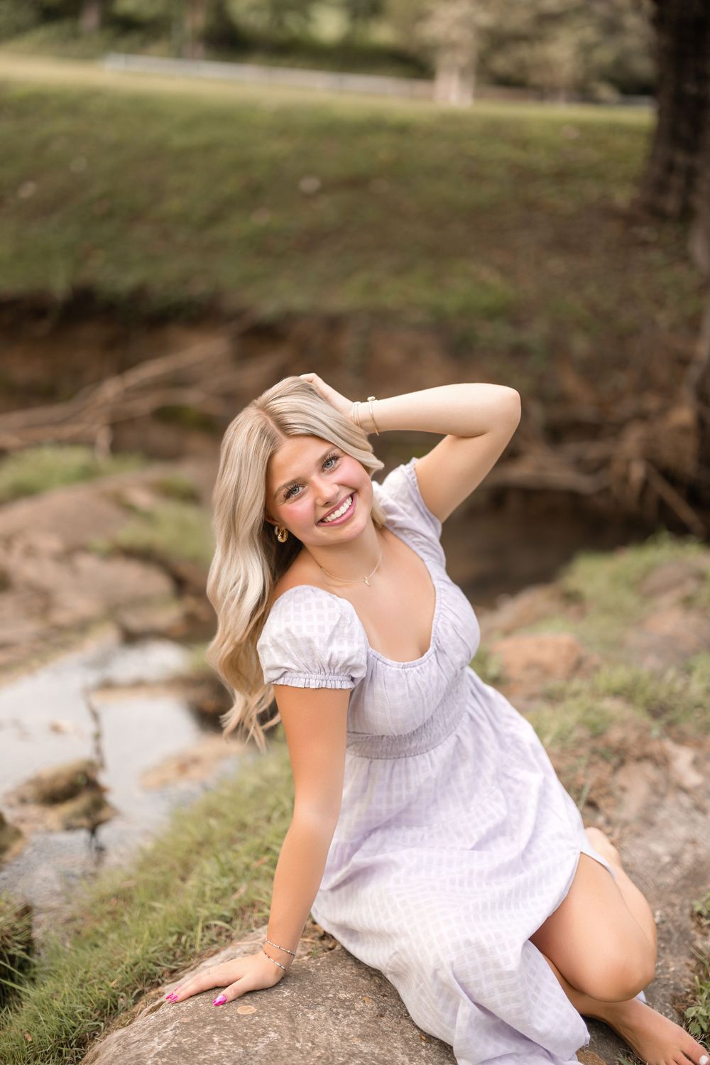 A casual outdoor portrait session near a creek with natural scenery and rocks.