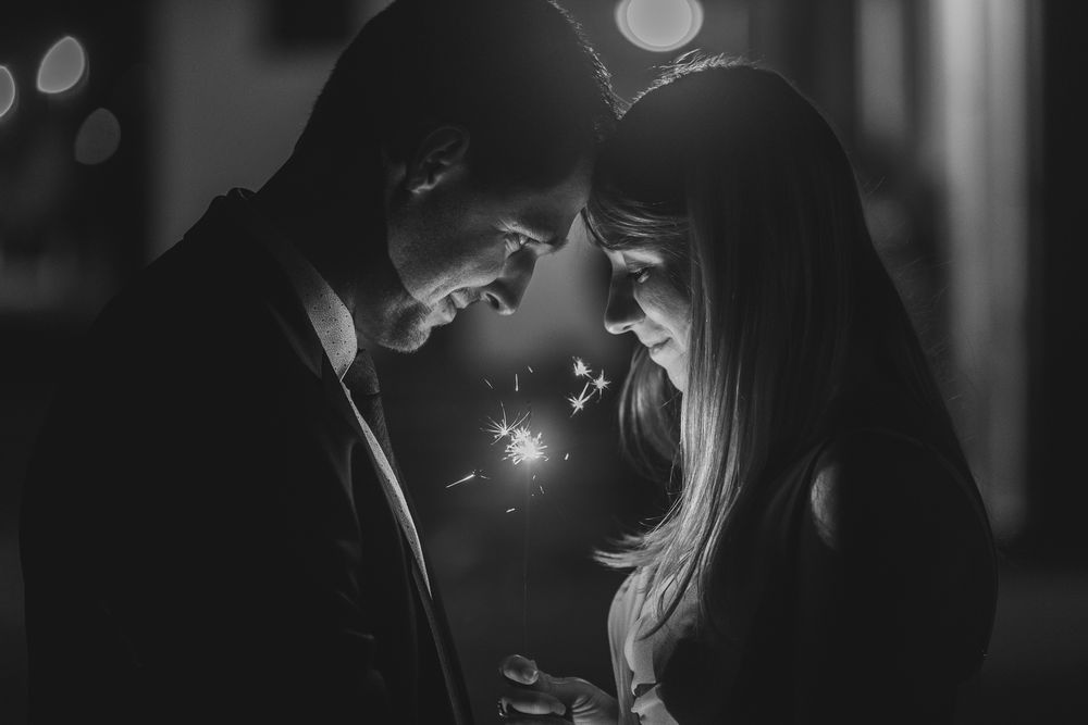 Black and white photo of romantic couple in dim lighting sharing tender moments.