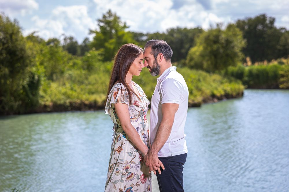 A tender engagement photo session by a tranquil lake surrounded by lush greenery.