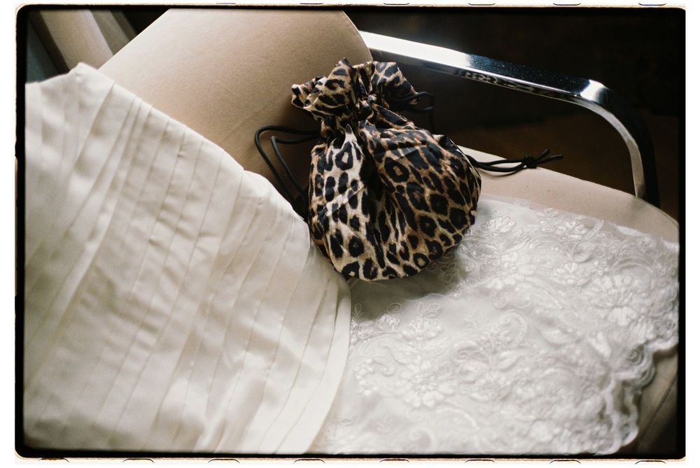 An abstract view of silky wedding dress fabric with leopard print accessories against a dark background.