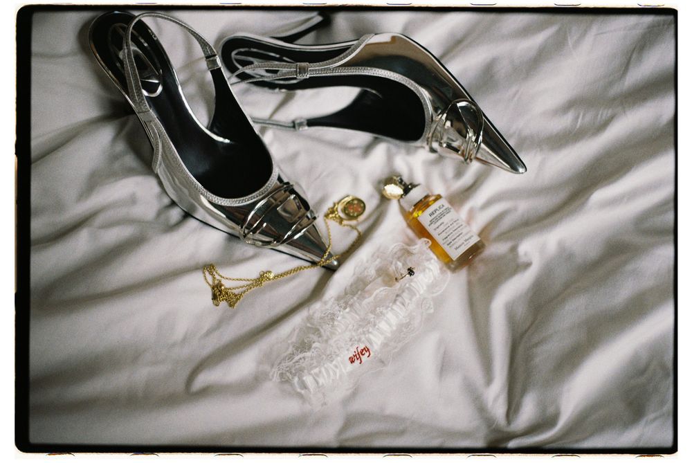Close-up details of leopard print stiletto heels and wedding accessories on white fabric.