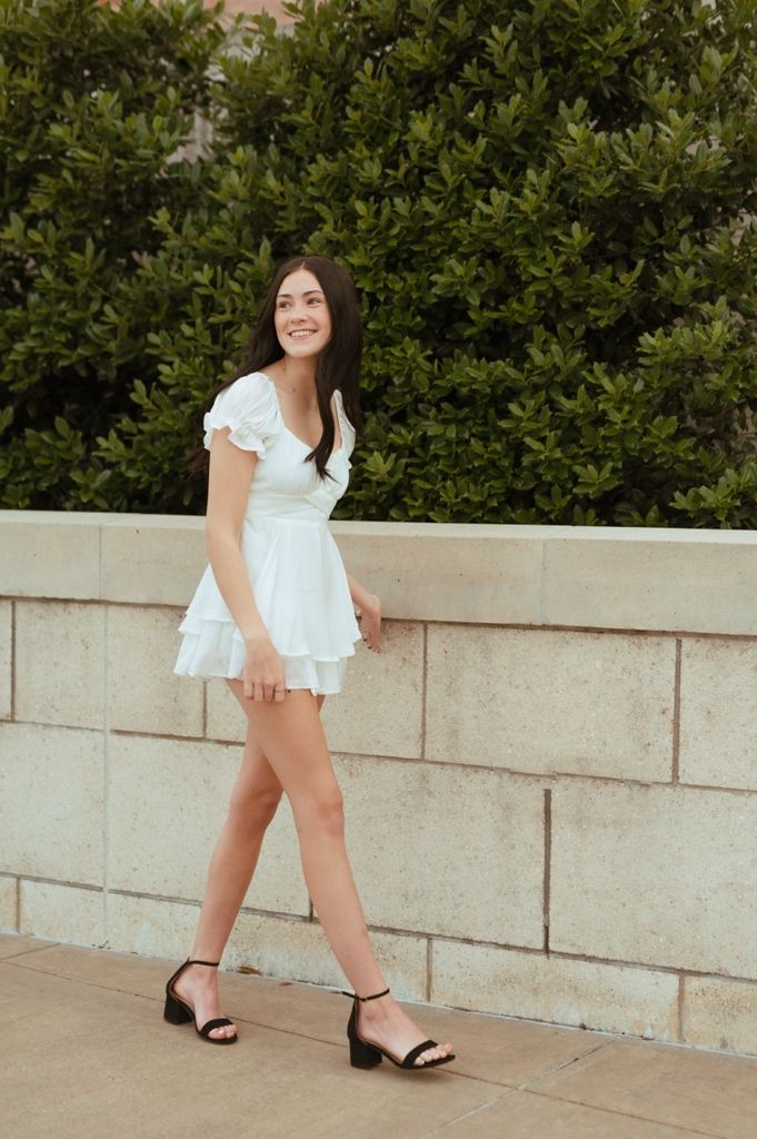 A sequence of photos showing someone in a white dress and black ankle strap sandals posing against a concrete wall.