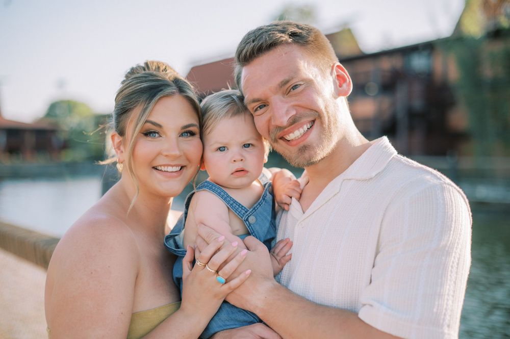 A joyful waterfront family portrait with a waterside backdrop during sunset.