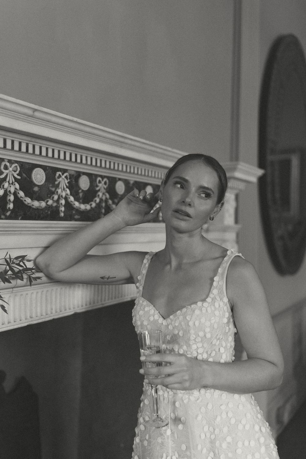 Black and white image of an elegant dressy sequined gown inside an ornate room with decorative molding and mirror.