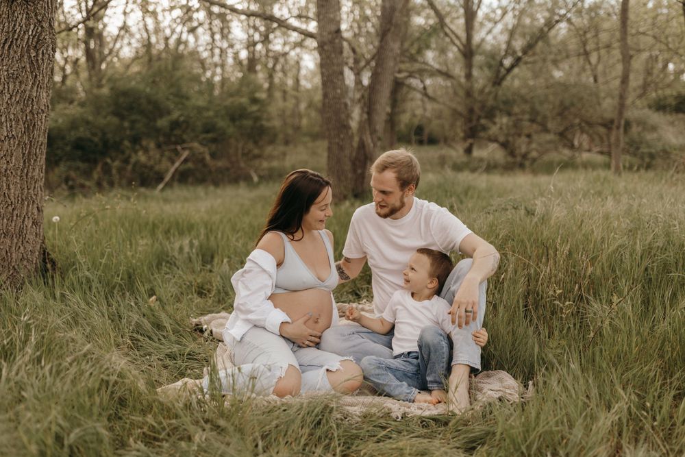 Intimate family photoshoot in a serene grassy field at sunset with a warm golden glow.