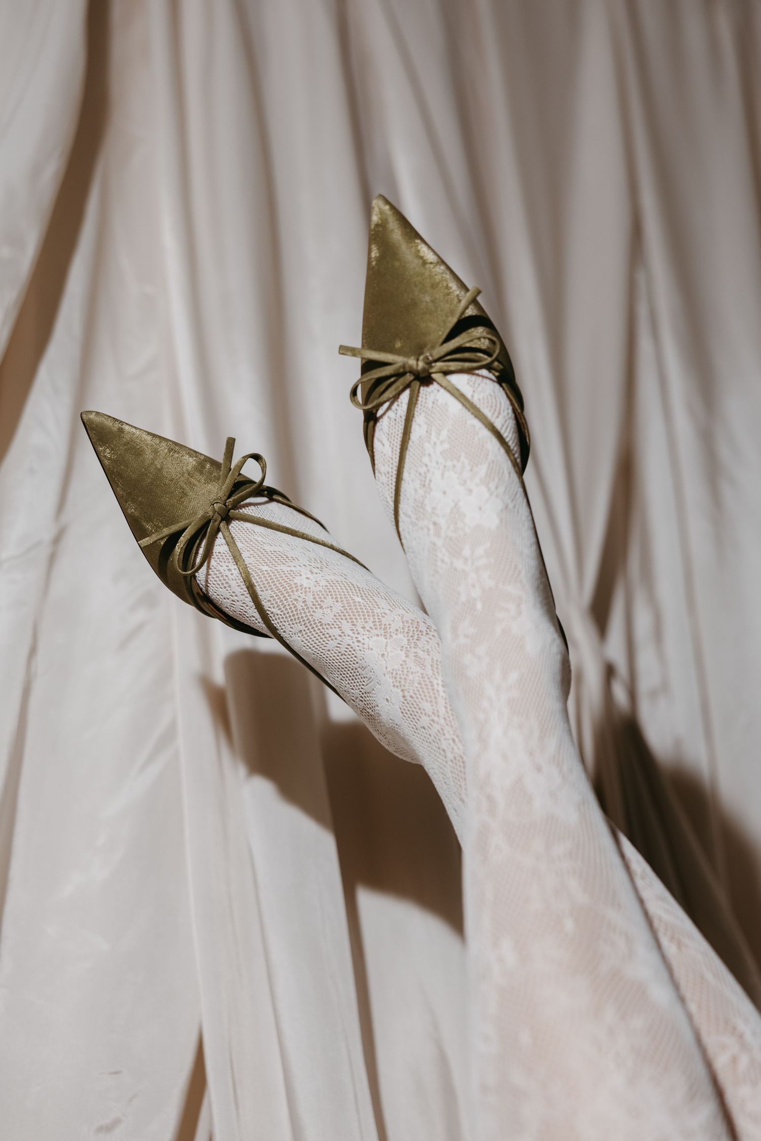 Gold vintage-inspired bridal shoes photographed against white fabric.