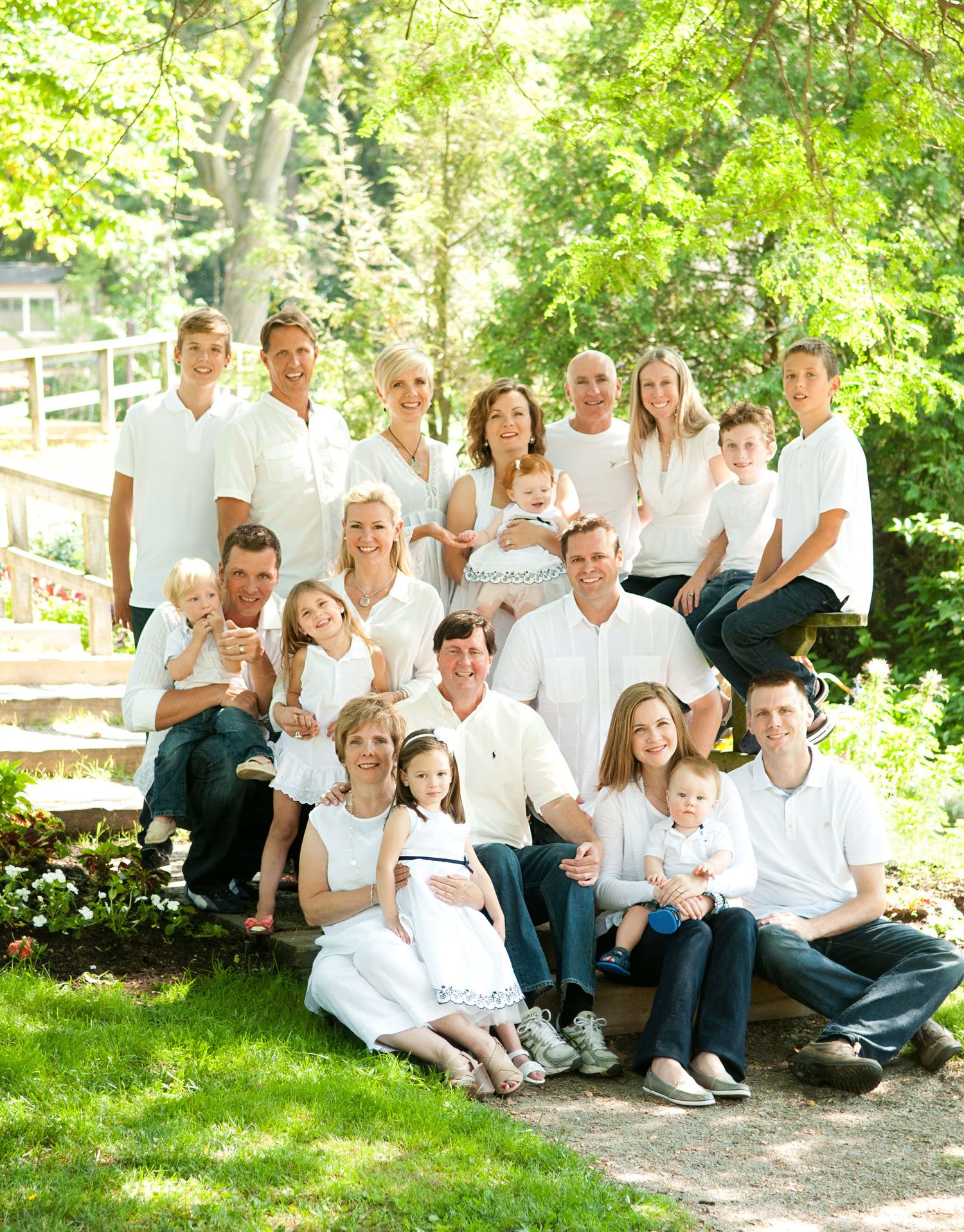 Large family group in white clothing poses together on outdoor steps in a garden setting.