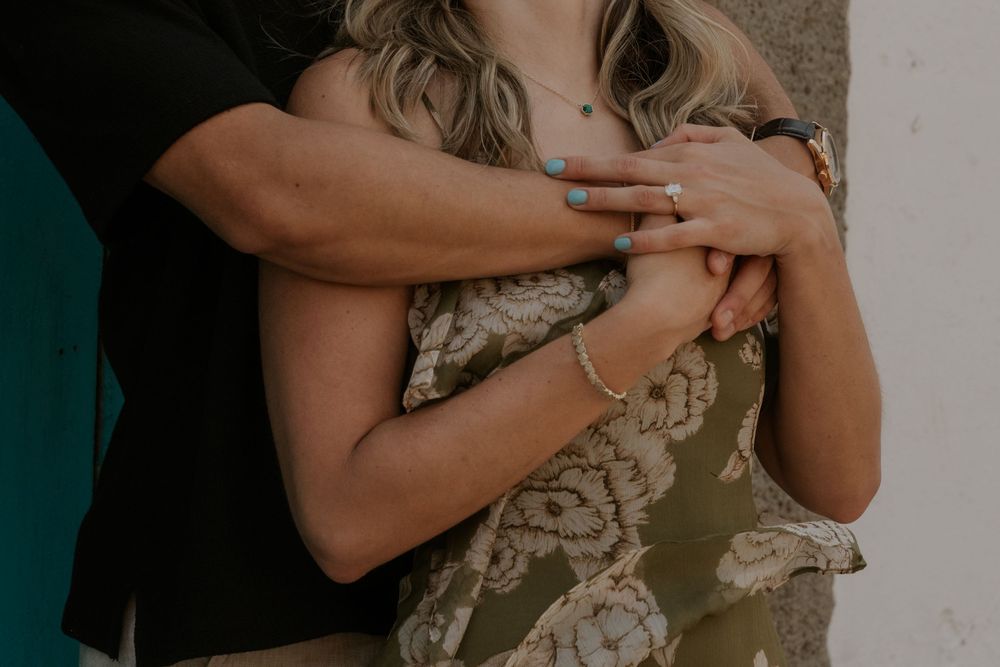 Arms crossed over chest wearing olive green dress with lace detail in moody natural lighting.