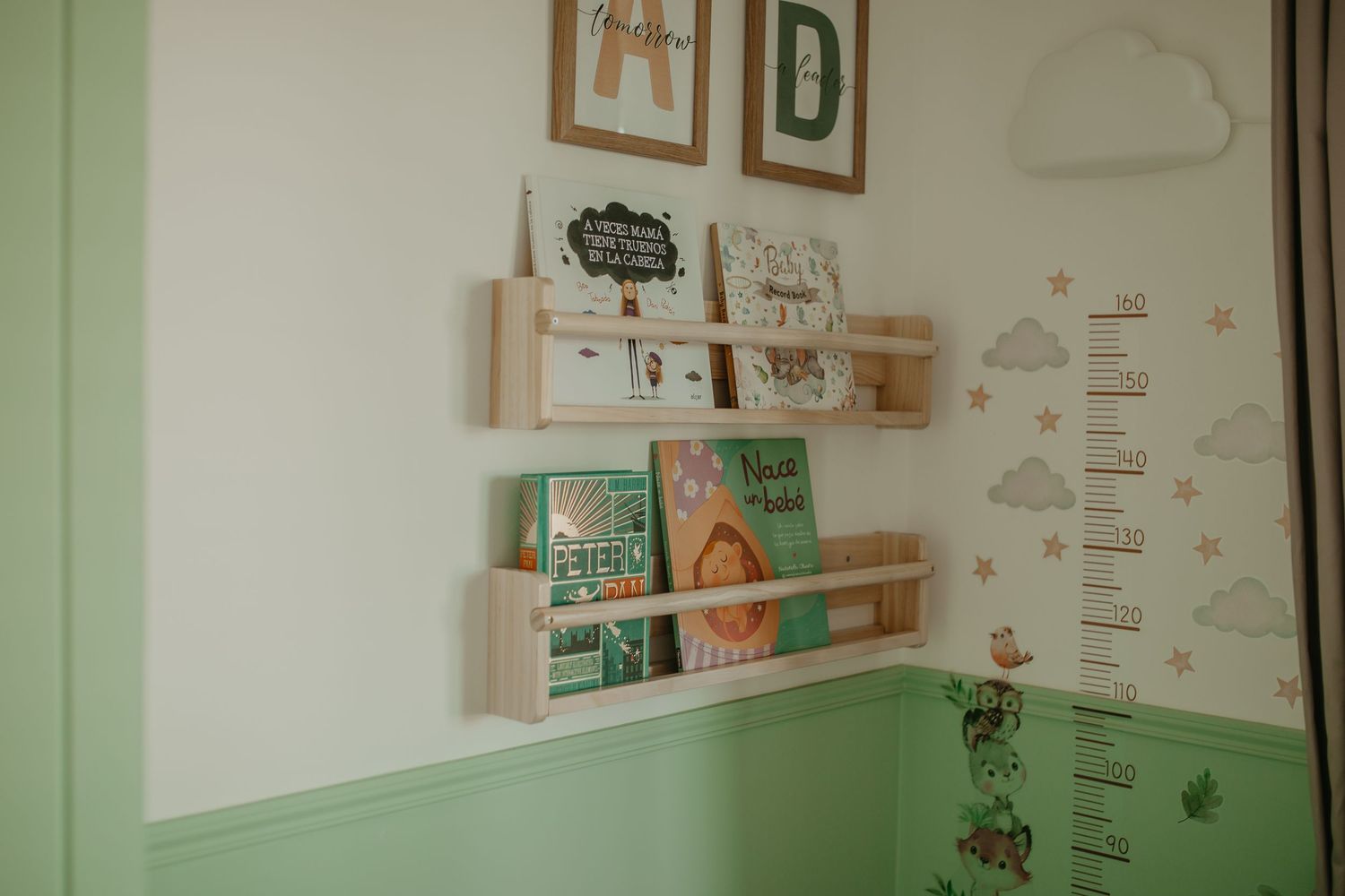 A modern sage green nursery room with decor, wall art, and a changing table arranged in a minimalist style.