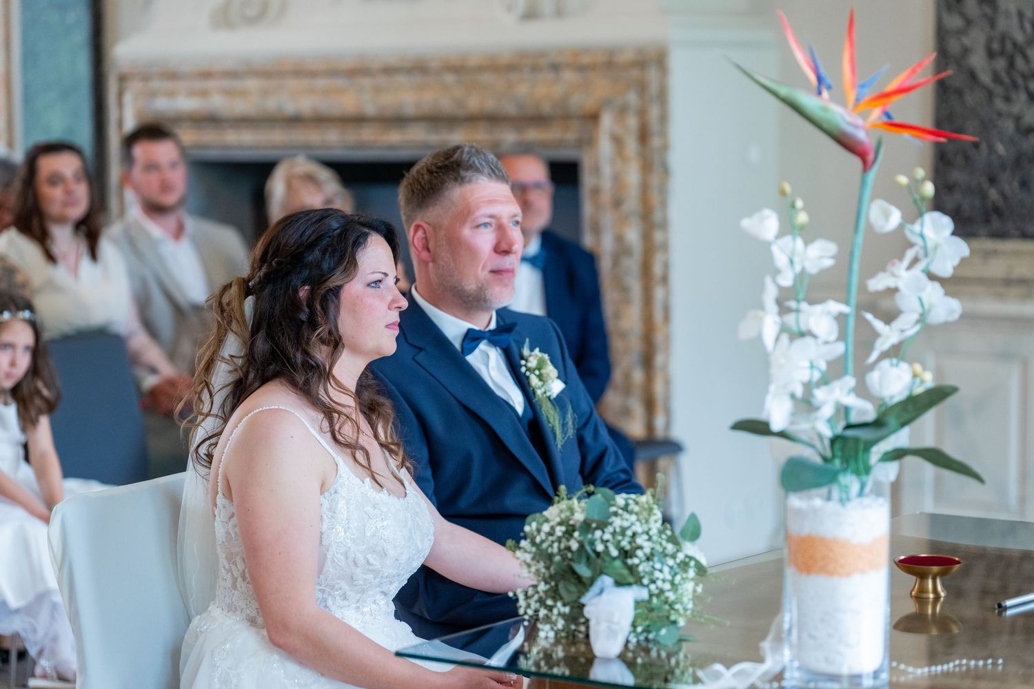 Brautpaar sitzt während der Trauung, Brautstrauß und Orchidee im Vordergrund, Schloss Mirow