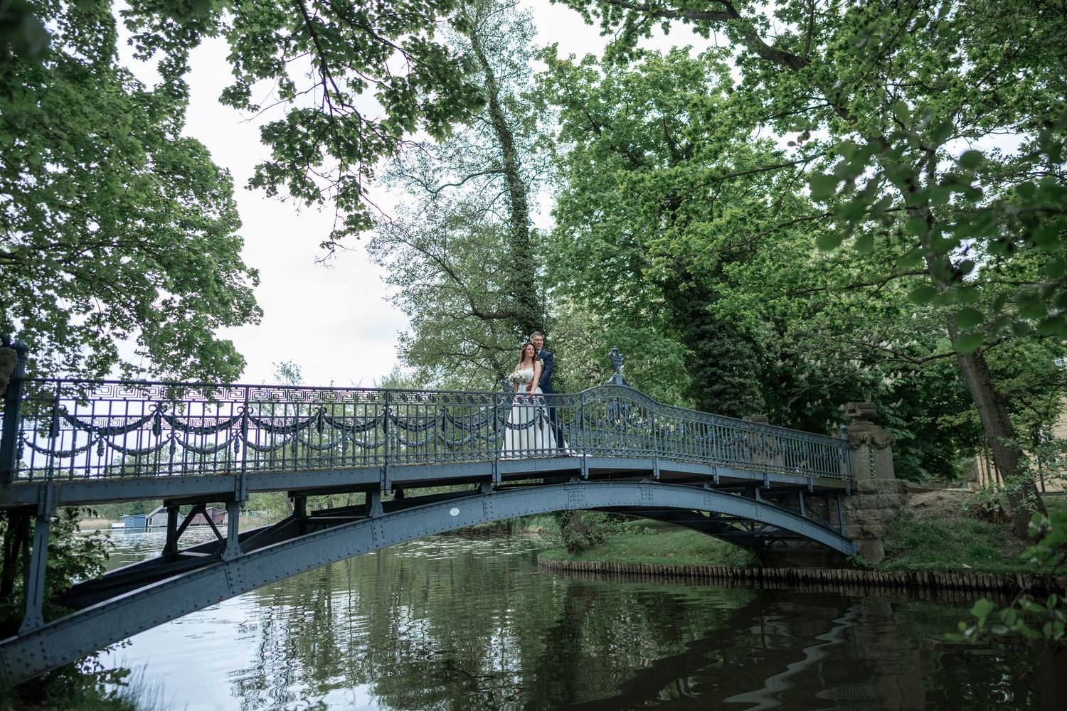 Brautpaar Hand in Hand auf Holzbrücke, Blick ins Grüne, Schloss Mirow