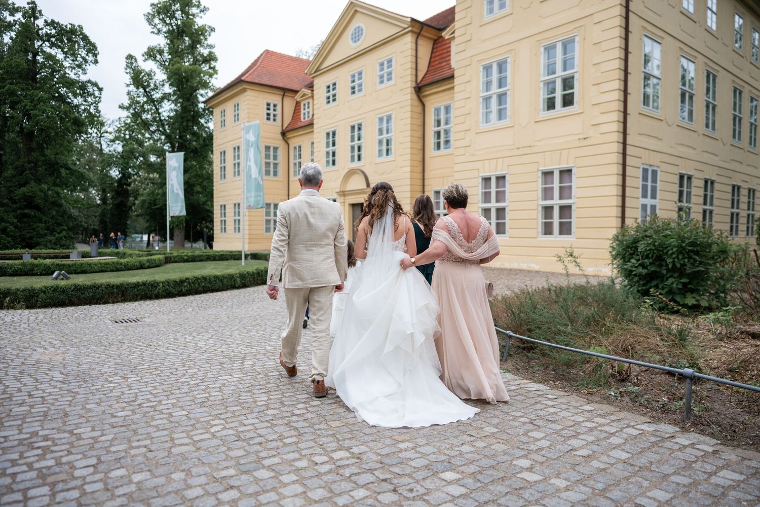 Brautpaar mit Trauzeugin auf dem Schlossvorplatz, gelbes Schloss im Hintergrund, Schloss Mirow