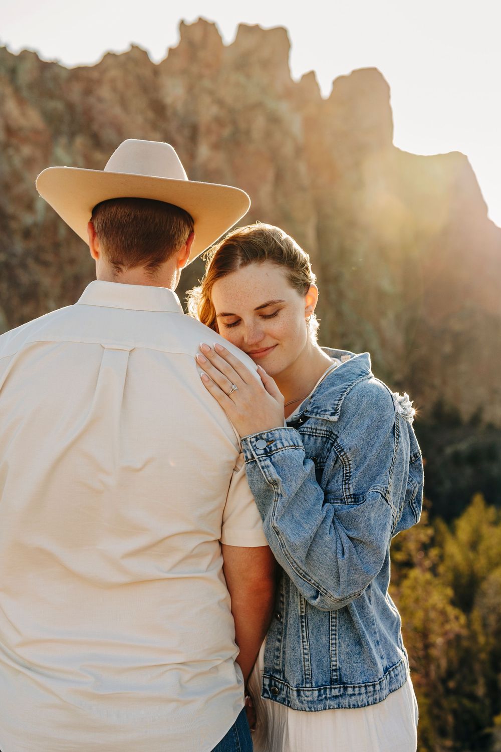 A romantic moment between a couple as one wearing denim jacket leans against another in cowboy hat.