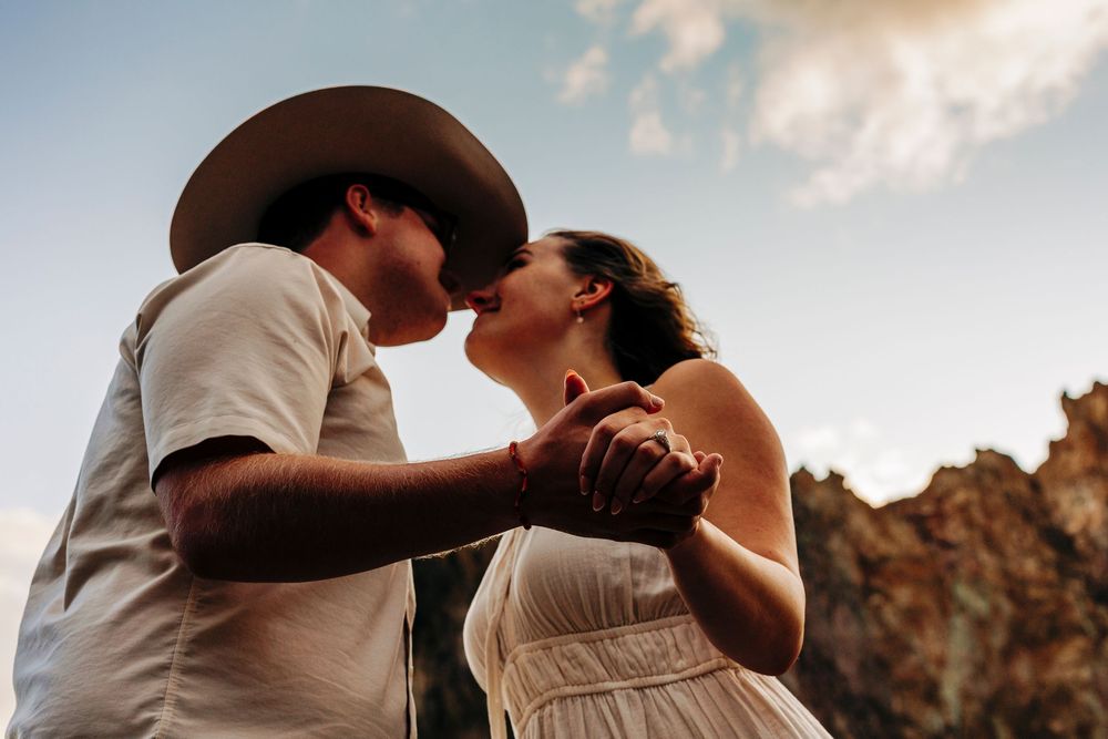 A romantic couple sharing an intimate moment at sunset, with dramatic rock formations in the background.