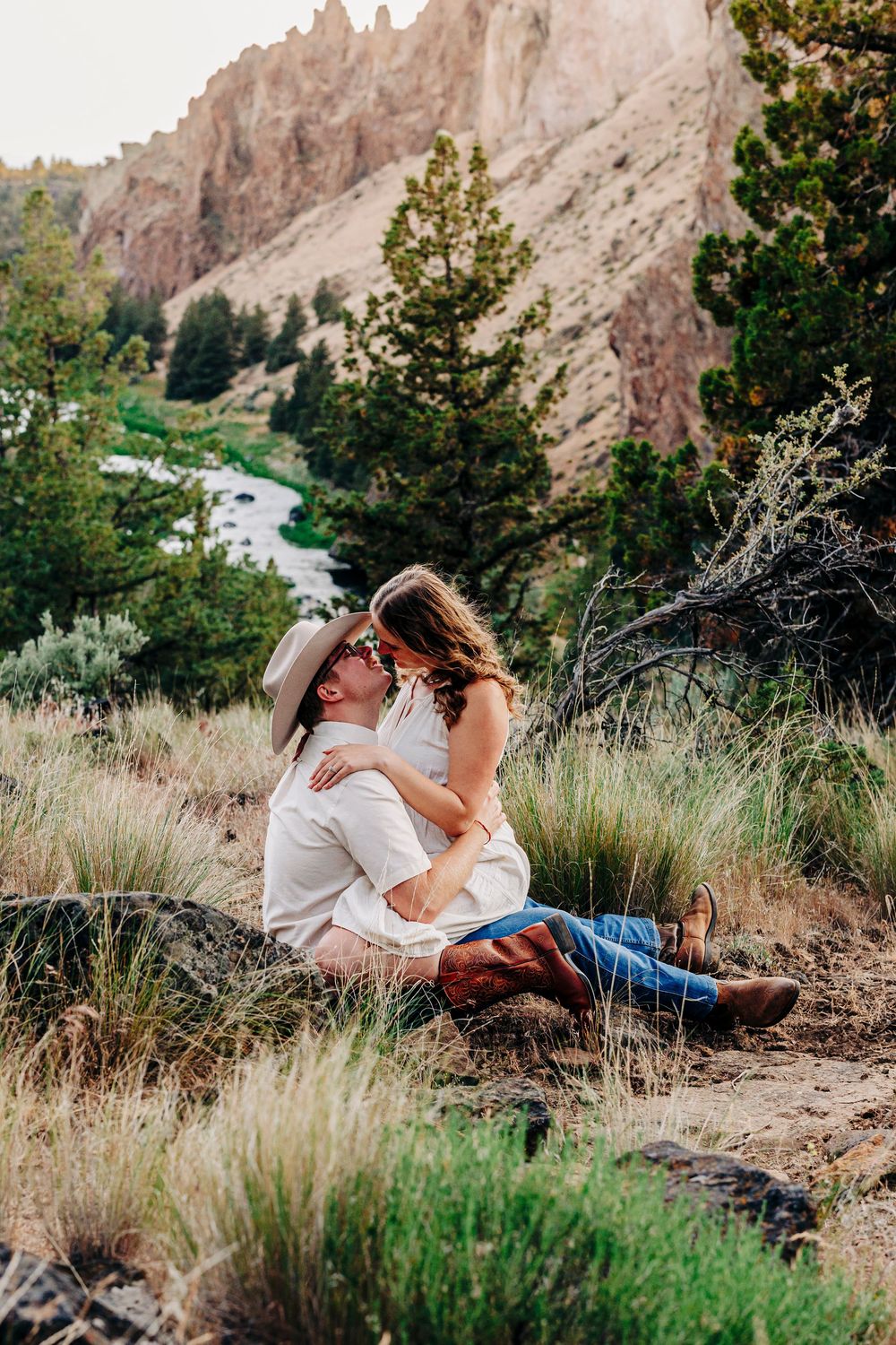 A romantic photo session in tall grass with towering rock formations in the background.
