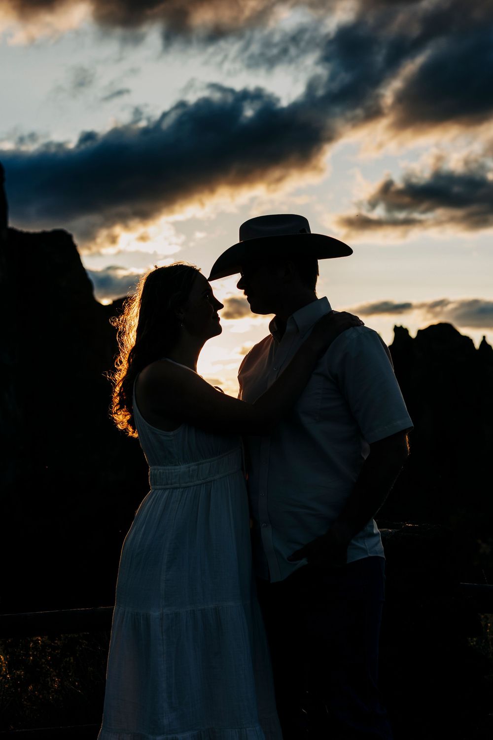 Silhouetted figures against a dramatic sunset sky wearing western attire.