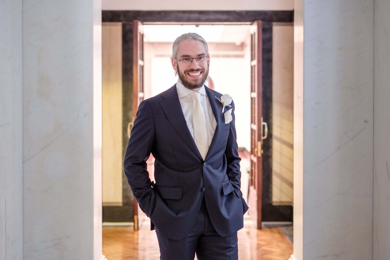 Four consecutive images of a businessman in a dark suit walking down a sunlit hallway or corridor.