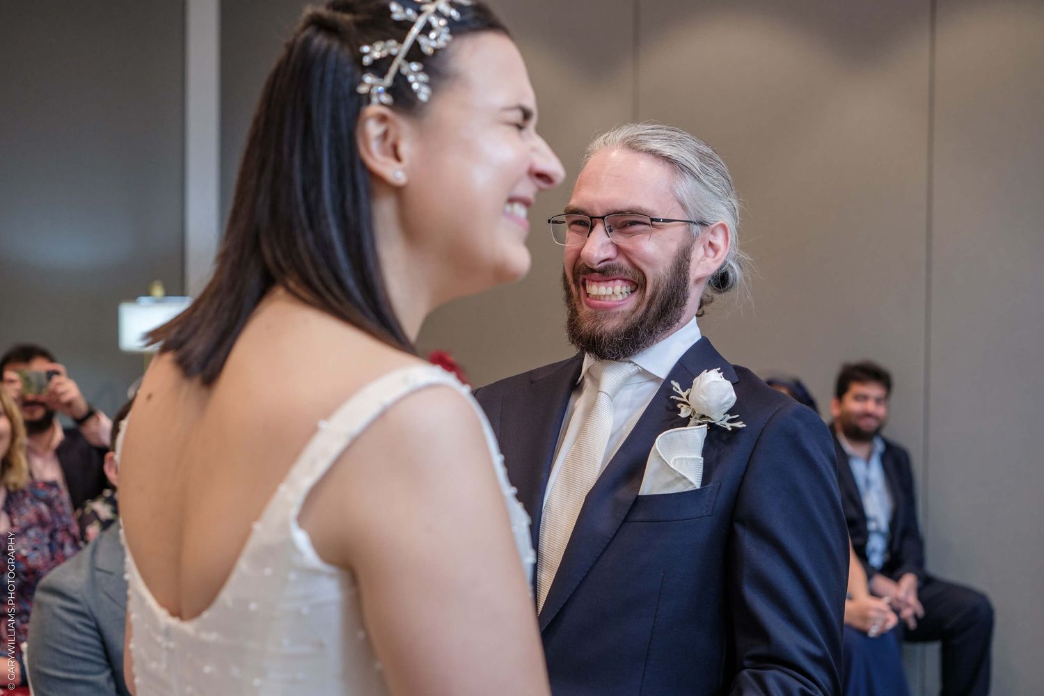 A joyful candid moment between two people sharing laughter during a wedding ceremony.