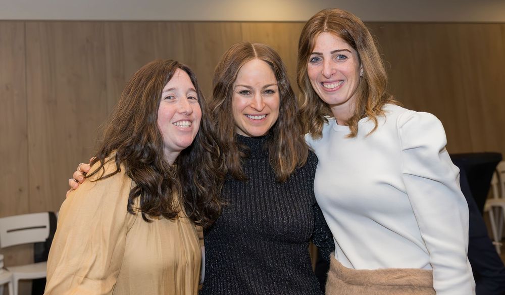 Group of people smiling together at an indoor event wearing formal attire.
