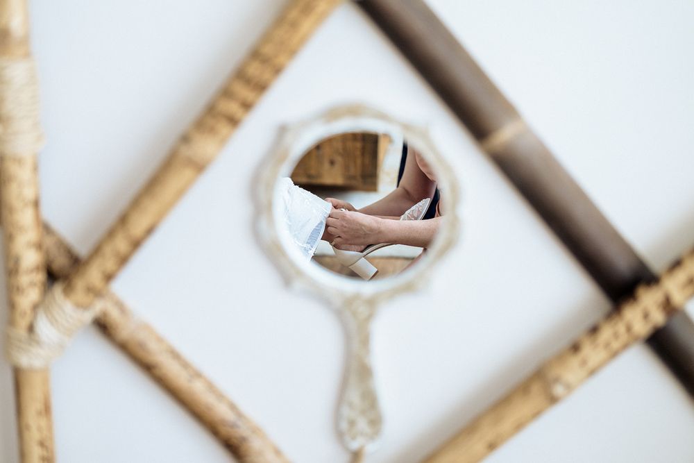 A circular handheld mirror reflecting a glimpse of entangled wooden lattice or trellis pattern in soft focus.