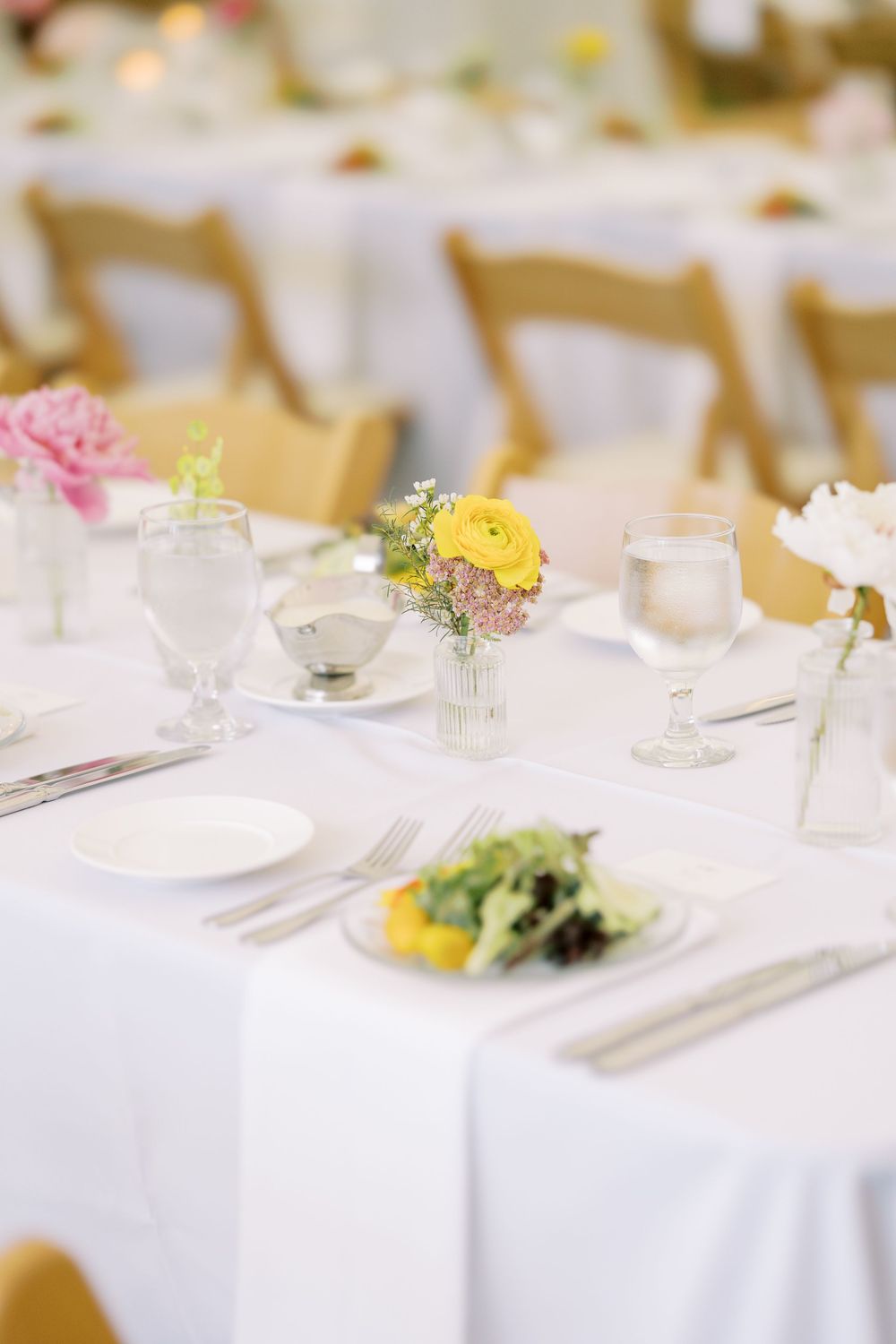Elegant wedding reception table settings with white linens, delicate floral centerpieces, and formal place settings.