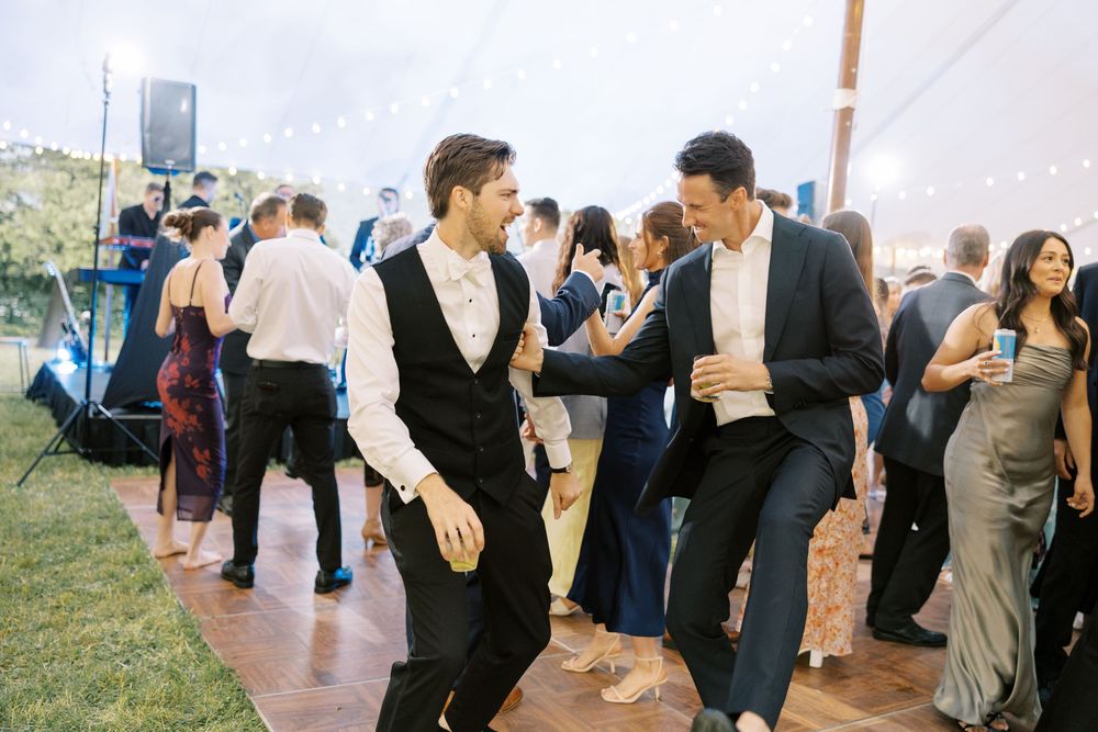 People dancing and celebrating at a wedding reception party on a sunny outdoor terrace.