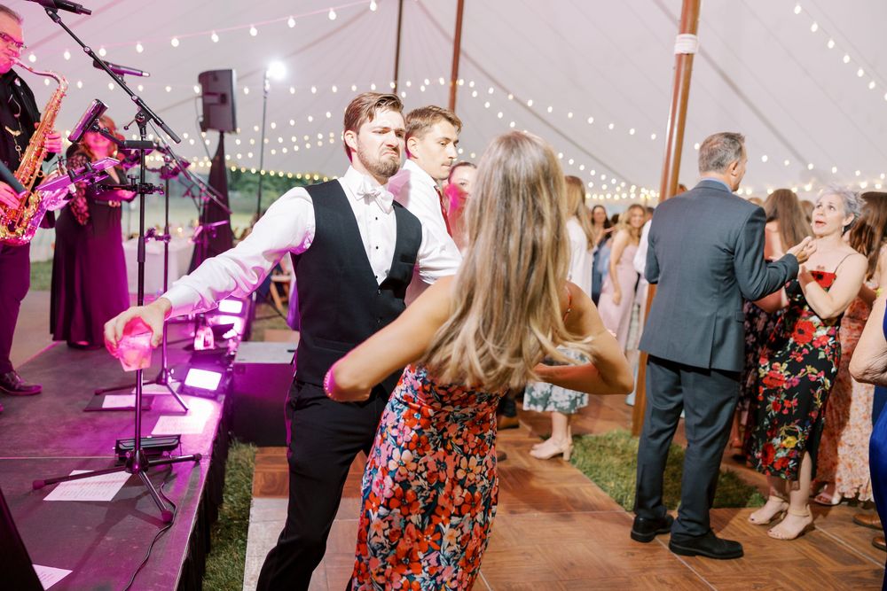 Wedding guests dance and celebrate on a string light adorned dance floor during an evening reception.