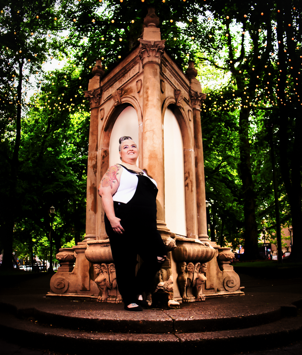 A dramatic portrait taken at a vintage stone gazebo surrounded by lush green trees.