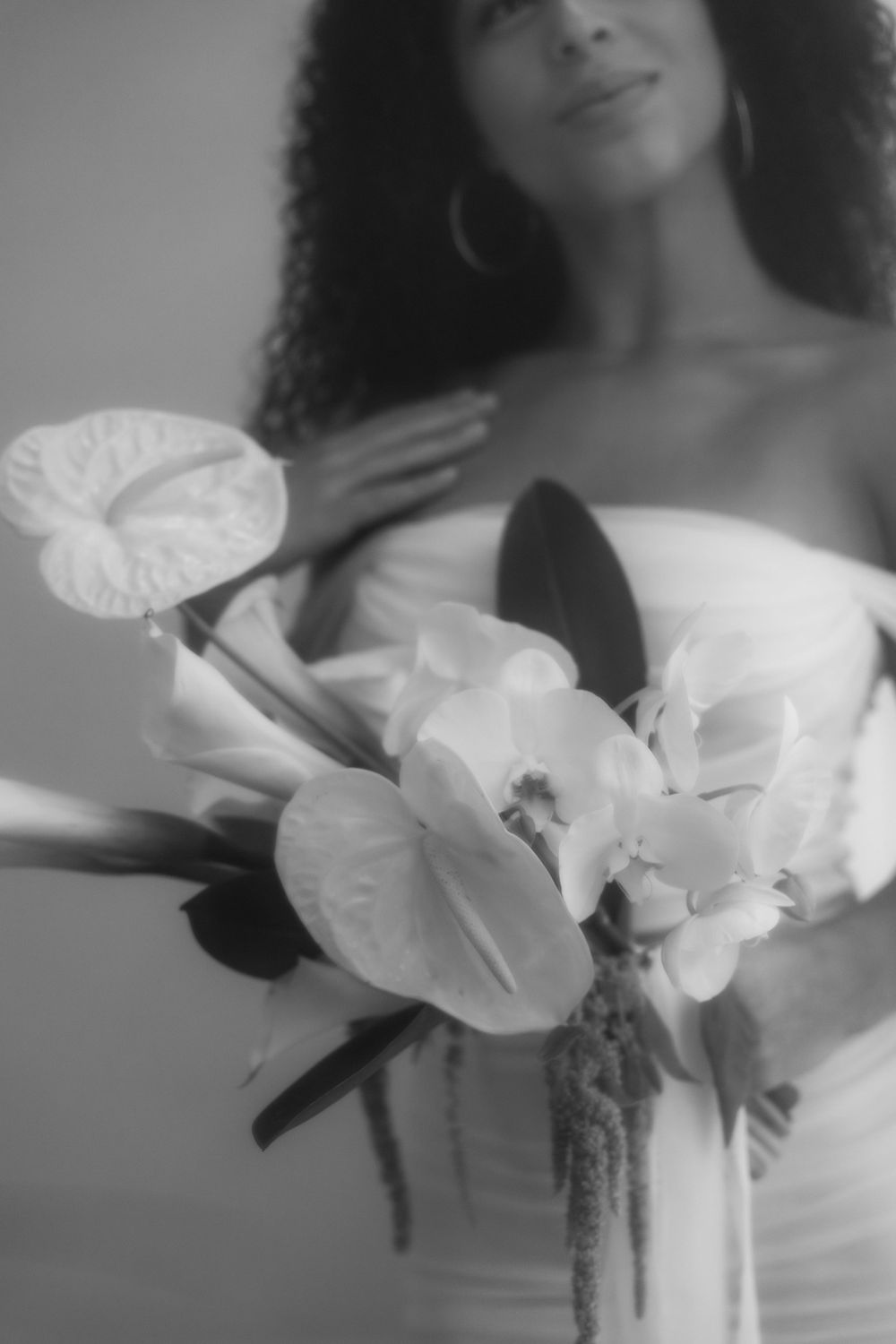 Black and white portrait with white orchids and delicate bridal details in soft, romantic lighting.
