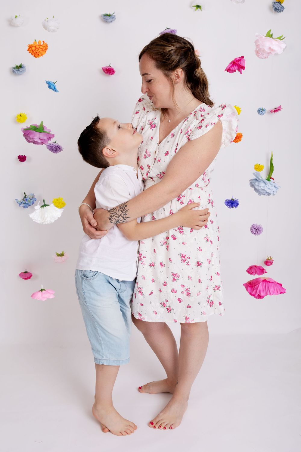 Parent and child sharing a tender moment while barefoot, surrounded by colorful paper butterflies against a white background.