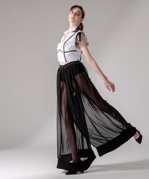 Fashion shot of sheer black palazzo pants with white collared blouse in studio setting.