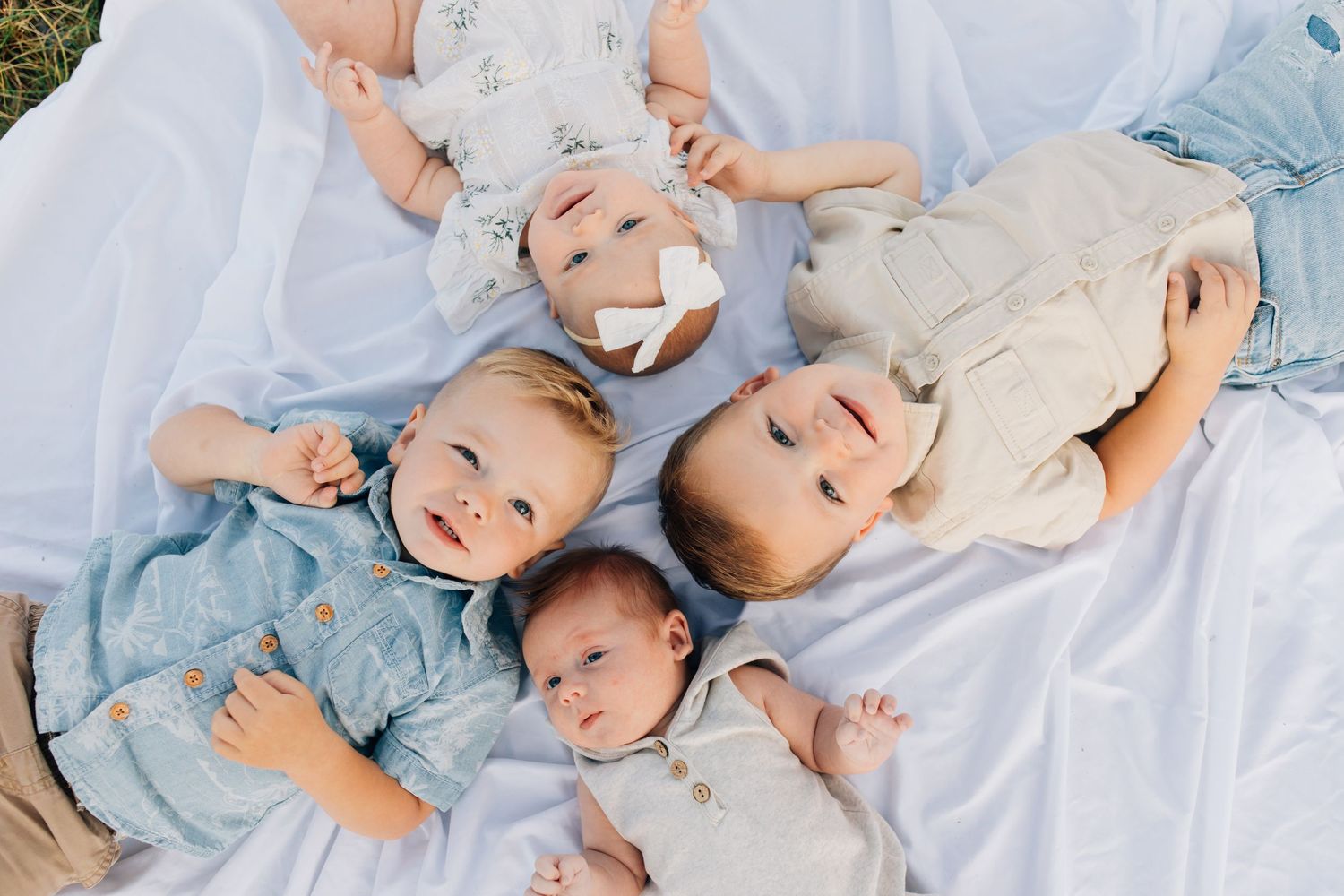 Four young children lying on a blanket looking up at the camera above them