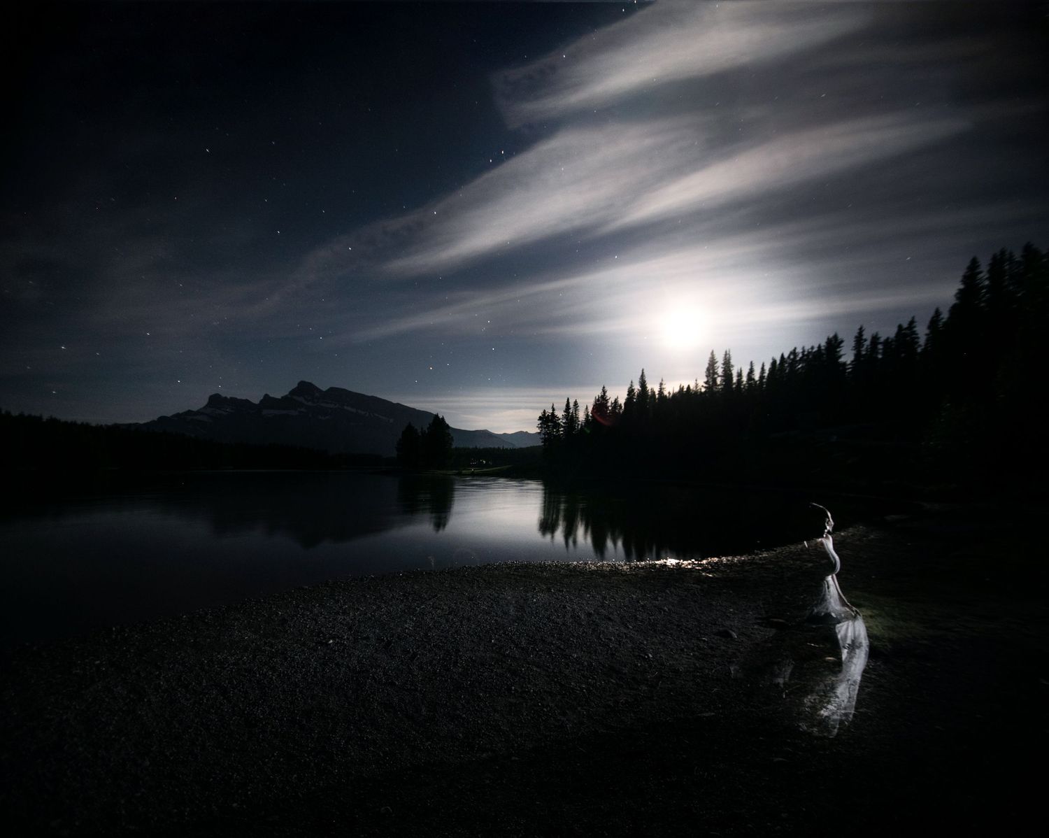 @ether.and.essence stands on rocky shore of TWO JACK LAKE UNDER THE MIDNIGHT SUMMER SOLTICE MOONLIGHT IN BANFF NATIONAL PARK CANADA