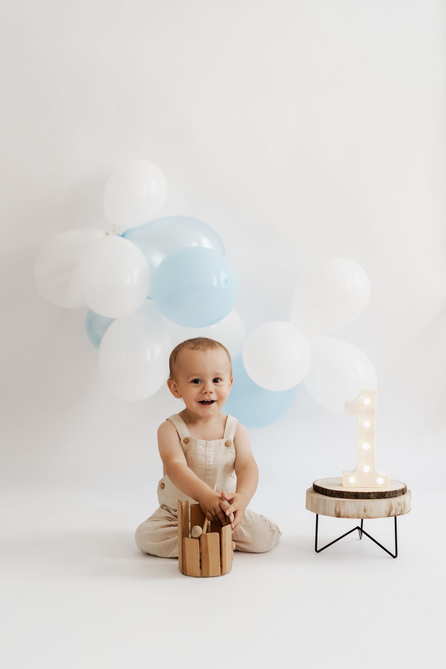 Kleiner Junge beim Geburtstagsfotoshooting im Fotoatelier Korneuburg, natürliches Geburtstagsfoto mit Luftballons und leuchtender Zahl 1