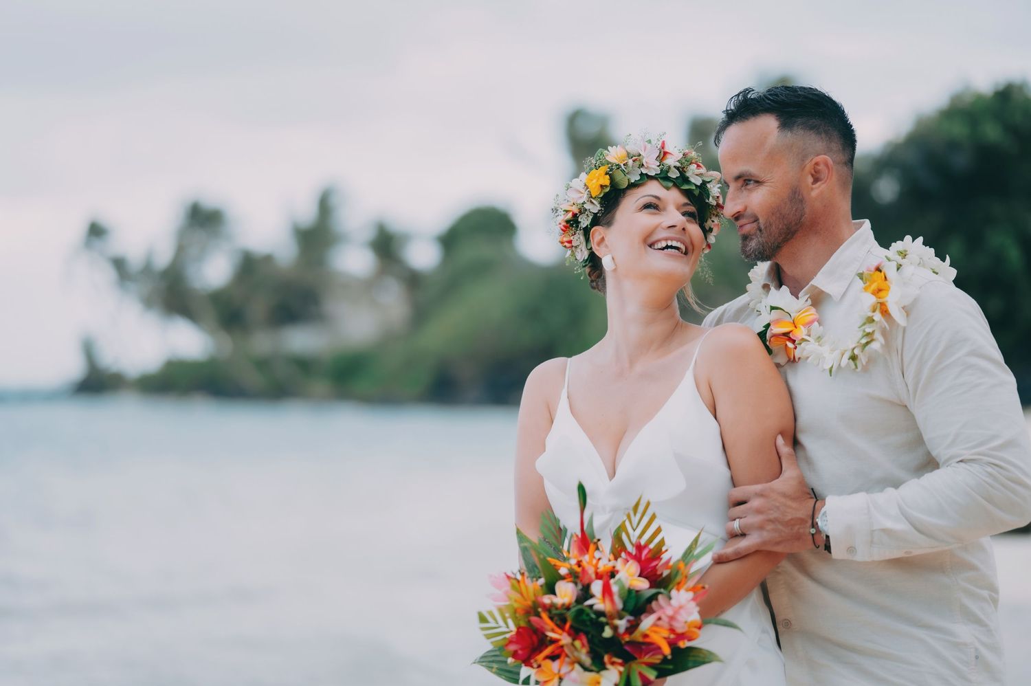 Joyful bride wearing a flowing veil gazes lovingly during an intimate outdoor wedding ceremony.