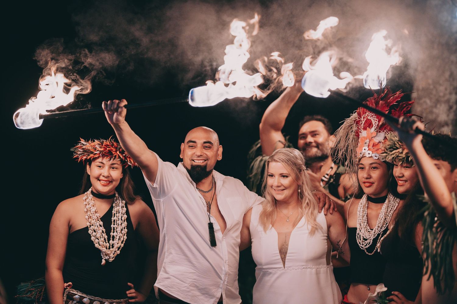 People enjoying a celebration with sparklers in hands during a night party while posing for group photo.