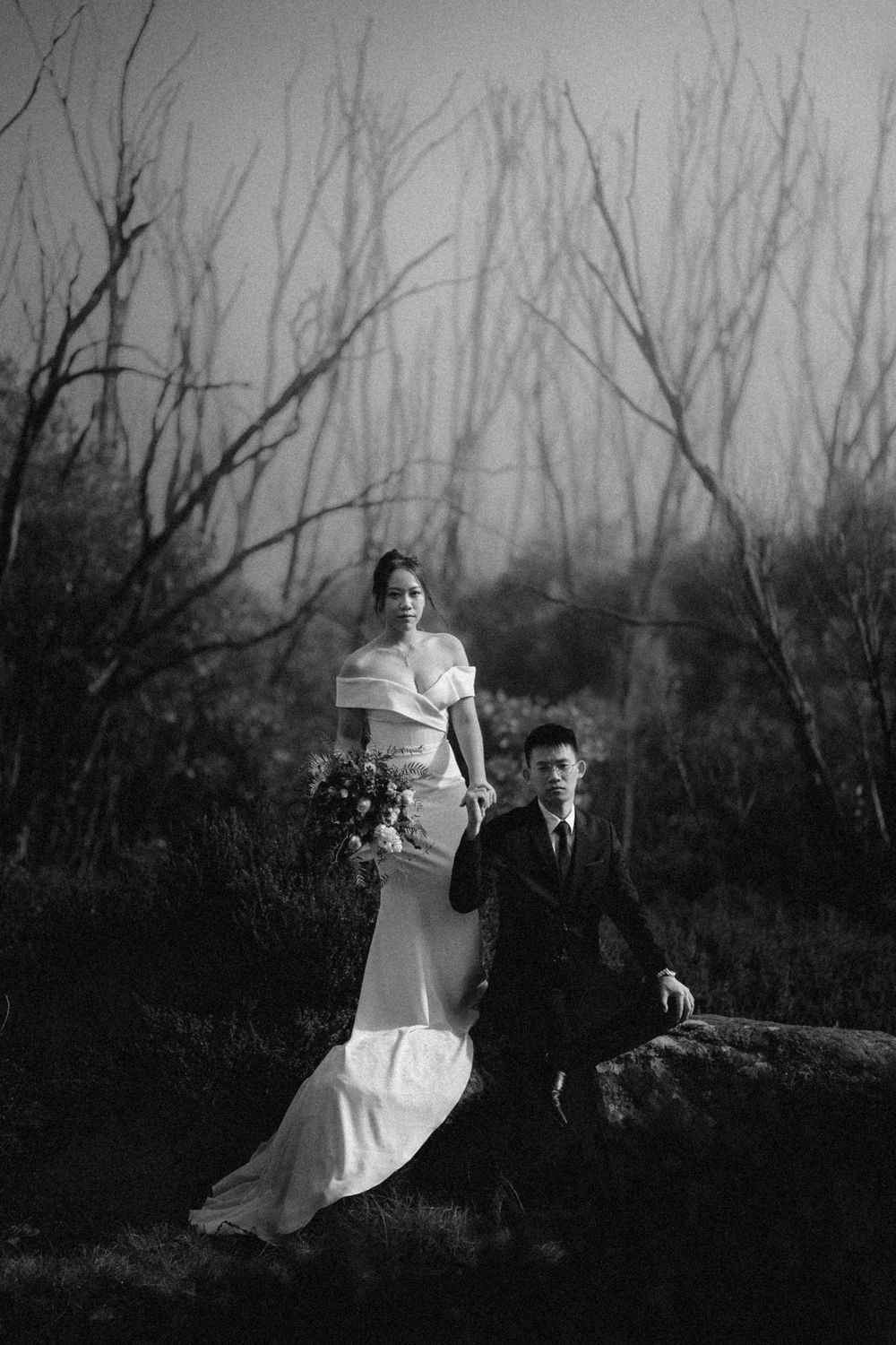 A black and white photo series showing a couple posing dramatically together in a winter forest landscape.