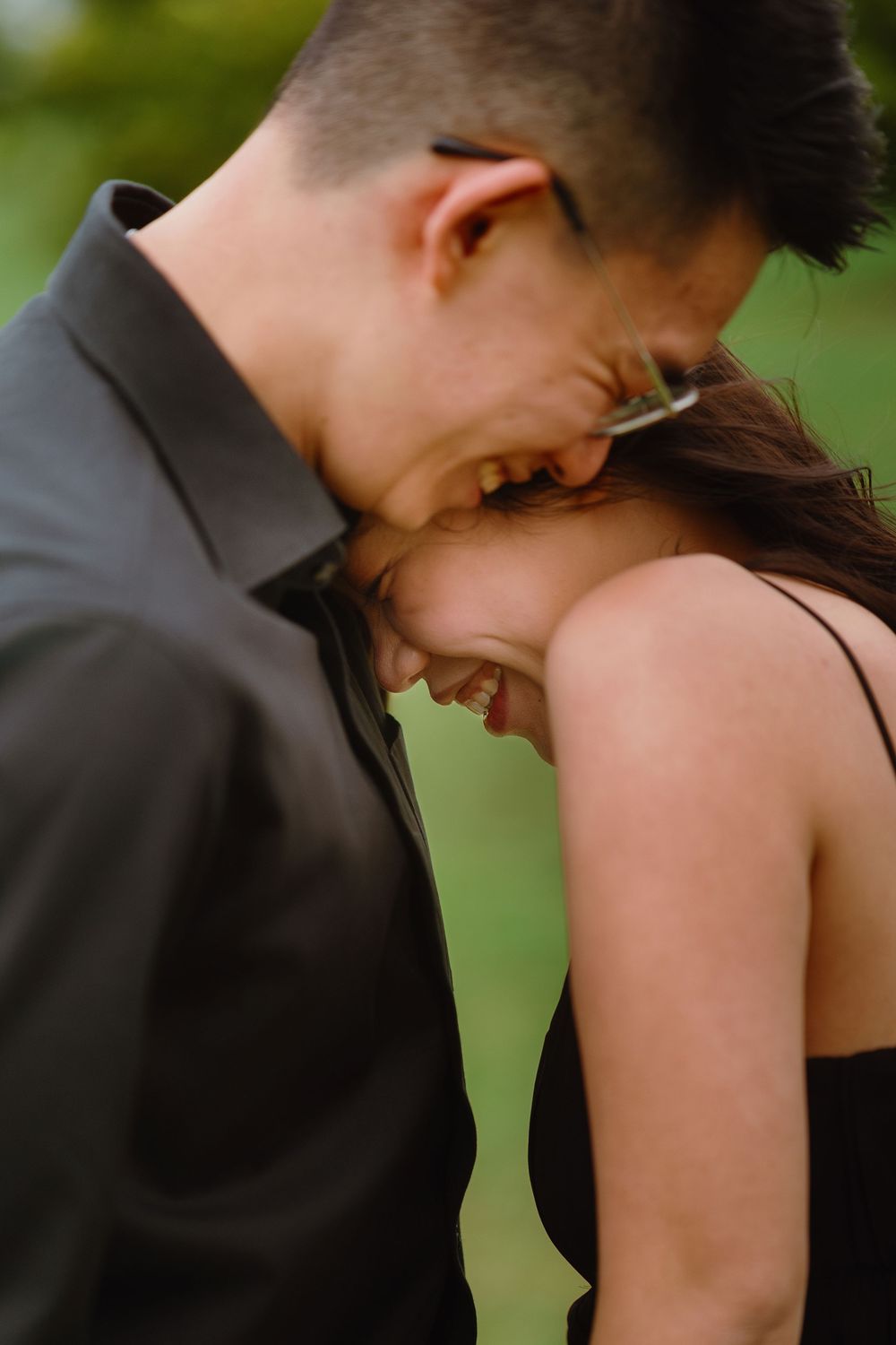 A couple sharing a tender laughing moment together as they lean in close with their foreheads touching.