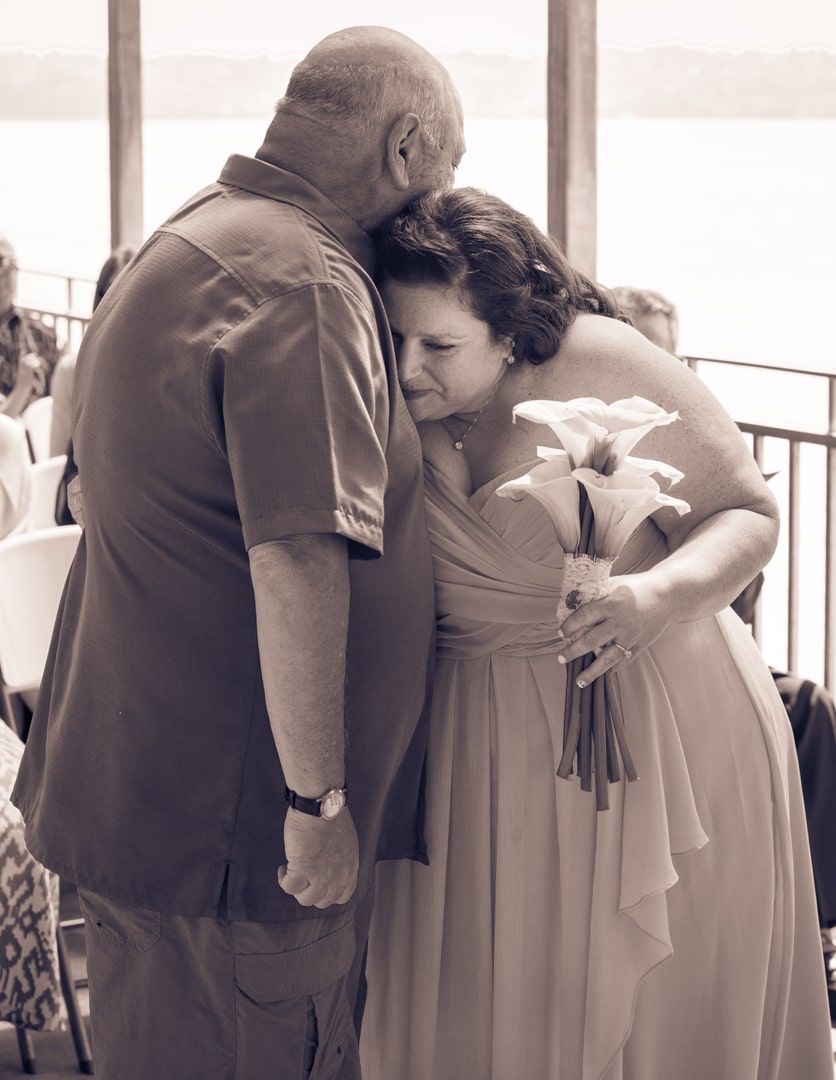 bride hugging dad just before she is given away to husband in sepia tone.