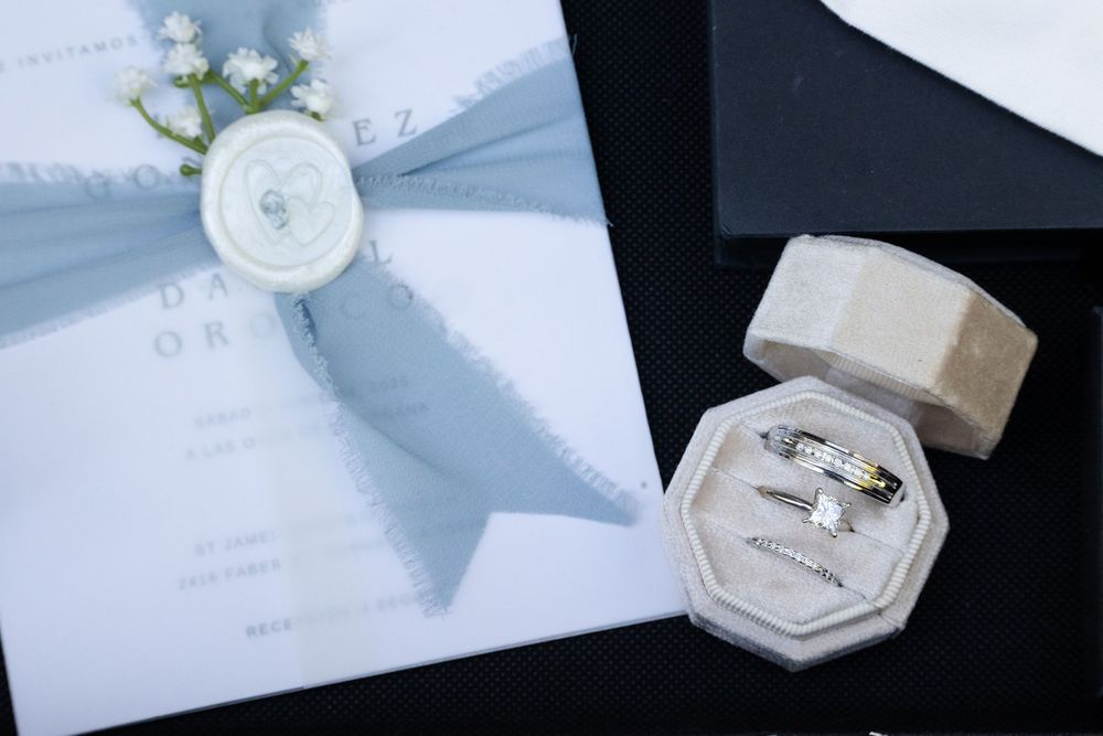 Wedding ring box and floral-decorated invitation on a dark background.