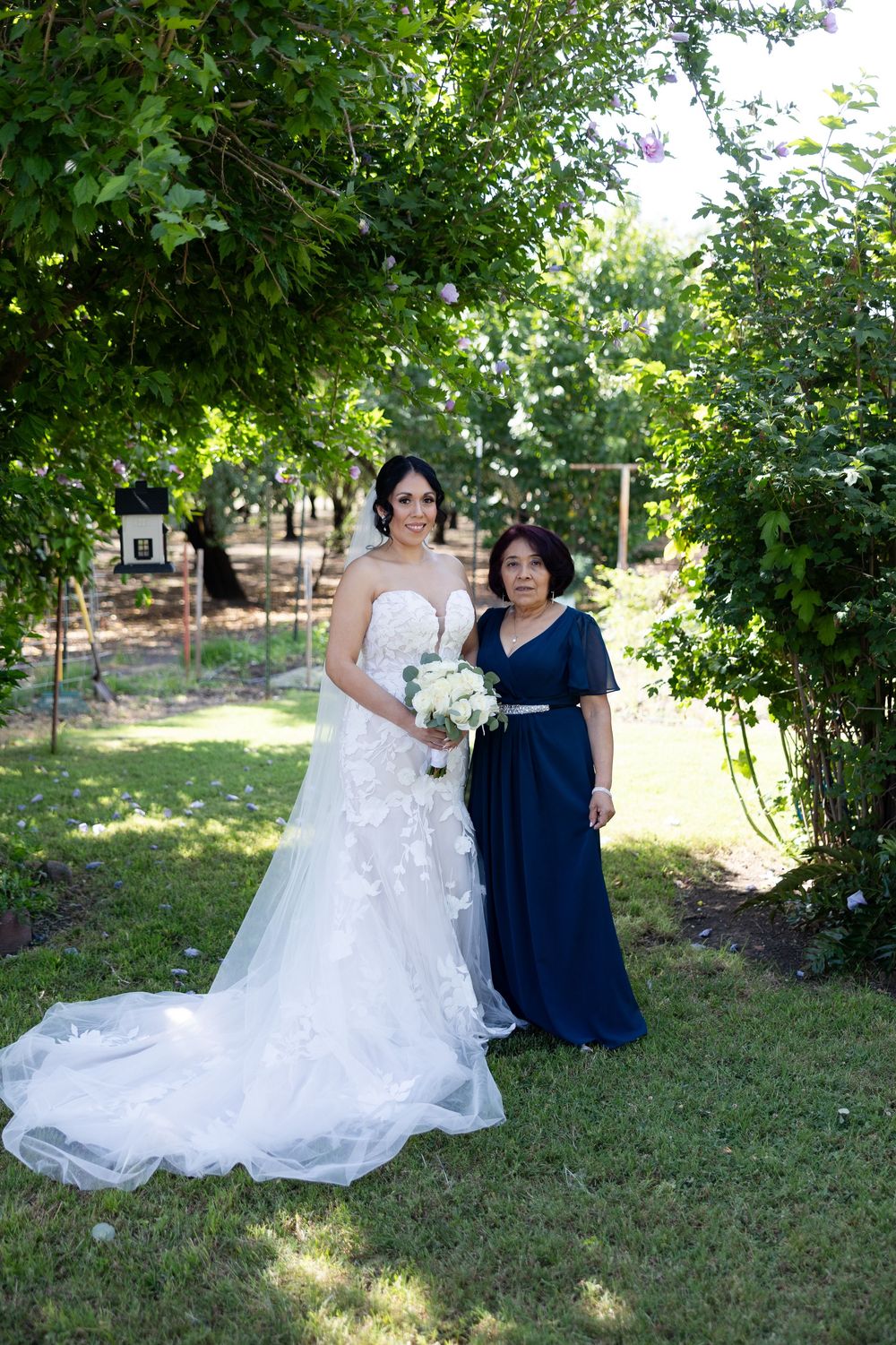 An elegant outdoor wedding portrait in a lush garden setting.