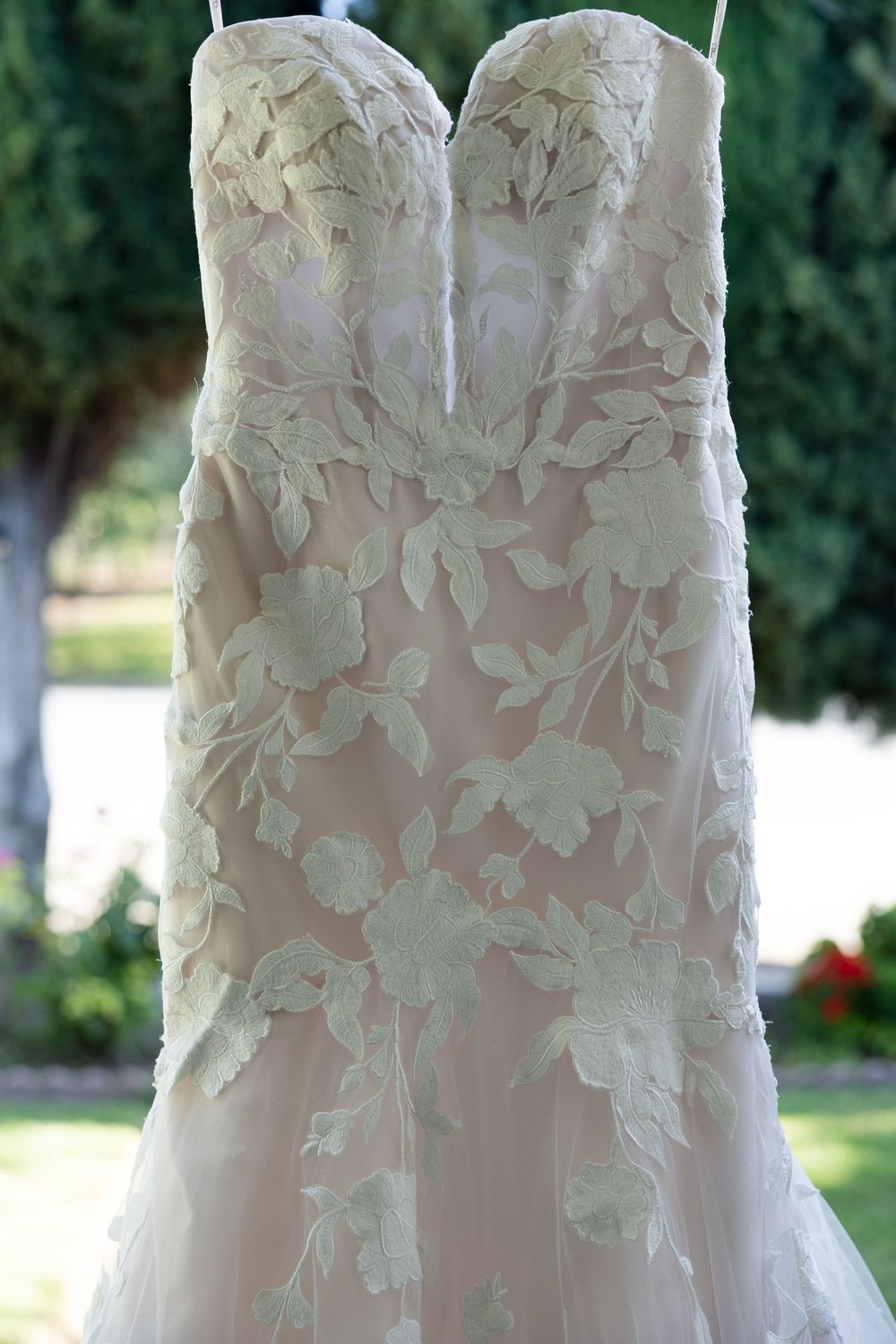 Close-up detail of a strapless wedding dress with intricate floral lace appliques.