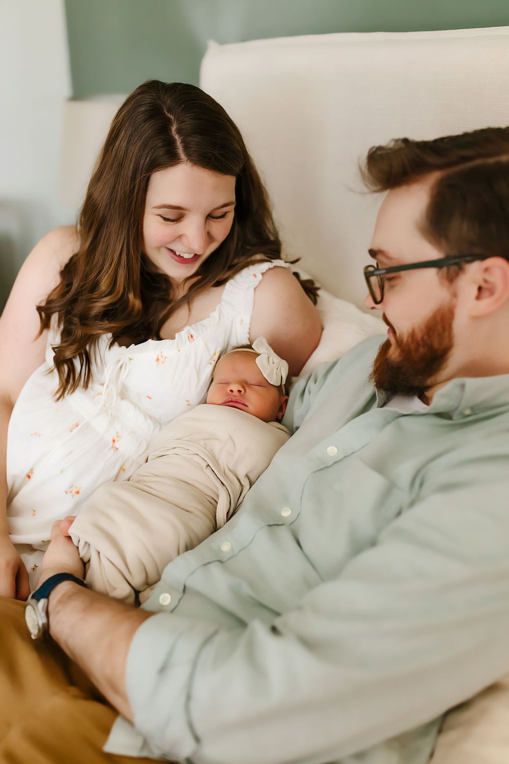 A loving couple shares a joyful moment with their newborn baby while relaxing at home.
