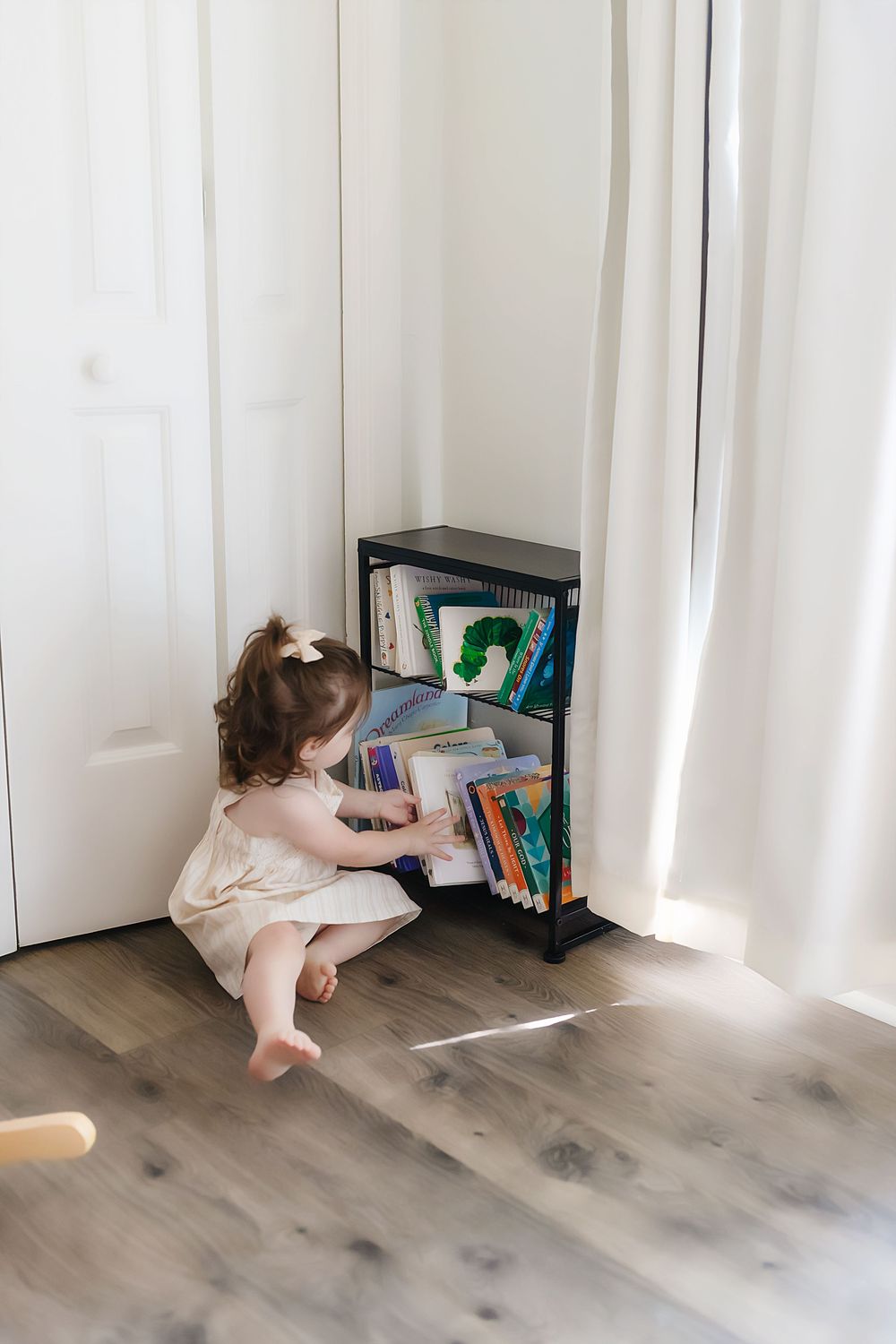 A series of photos showing someone crawling across a floor toward a small bookshelf in a bright room with white curtains.
