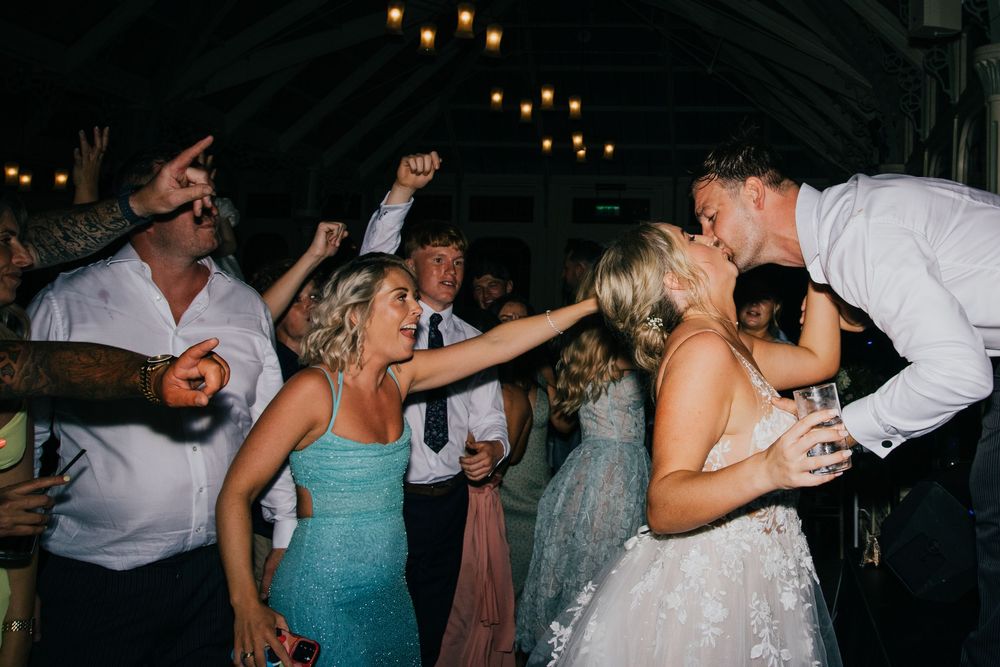 A string of consecutive party photos showing wedding guests dancing and celebrating at a reception with hanging lights.