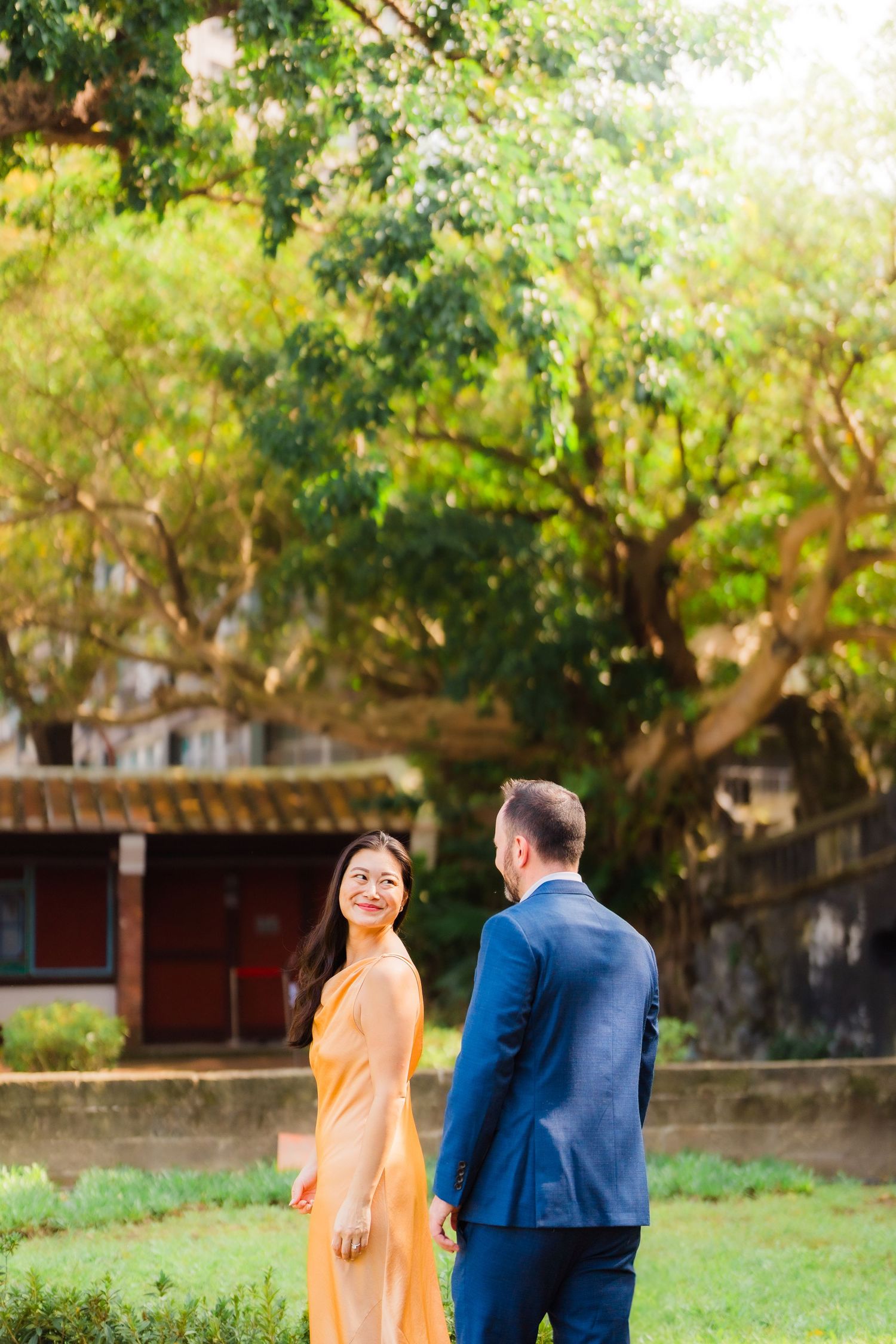Romantic couple embraces in dramatic dip pose at ornate Chinese temple doorway illuminated by warm lighting.