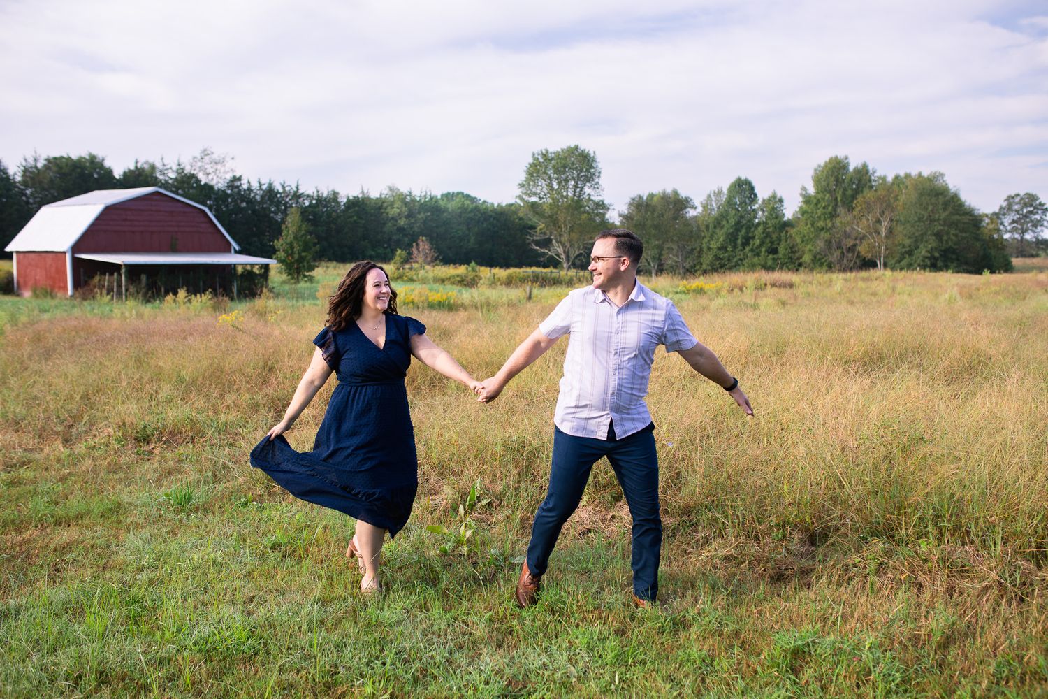 a couple run joyfully across an open meadow at sunset at Juniper Creek Farm